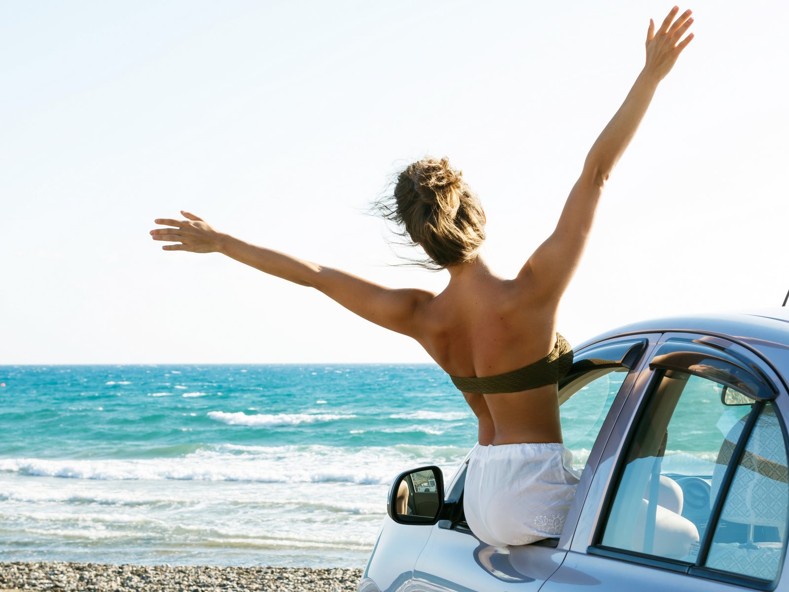Happy woman and car on the beach